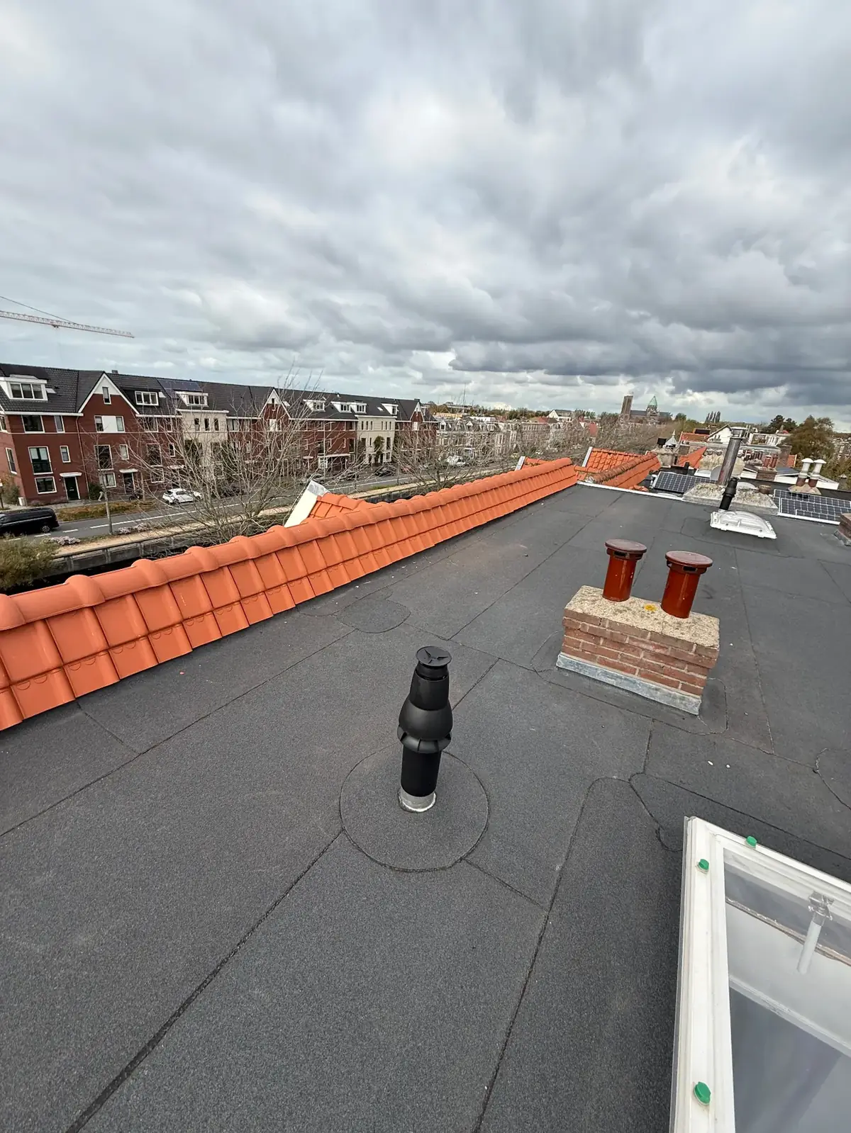 Dakwerken op platdak met schoorsteen en ventilatiepijpen